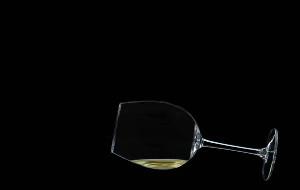 A glossy glass of white wine lies on black background with copy space — Stock Photo, Image