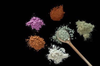 Tahta bir kaşık yüz ve vücut için kuru tıkanmış kil maskesi. Siyah arka plan üzerinde yalıtılmış