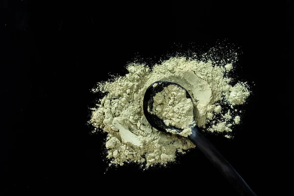 Dry green clay mask for face and body in a wooden spoon. Isolated on a black background — Stock Photo, Image