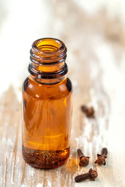 Flaska organiska kryddnejlikor eterisk olja. torr produkt sprids på en trä bakgrund — Stockfoto