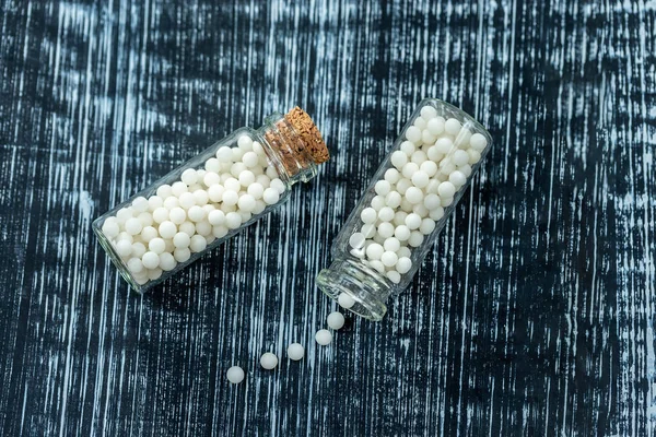 Natura morta concetto di pillole omeopatiche con granuli omeopatia su uno sfondo di legno grigio — Foto Stock