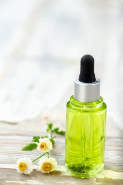ahşap bir arka plan üzerinde bir damlalık şişede papatya esansiyel yağ