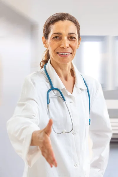 Glimlachend zelfverzekerde vrouwelijke dokter glimlacht en geeft een handshake aan de kijker, Point of View shot — Stockfoto
