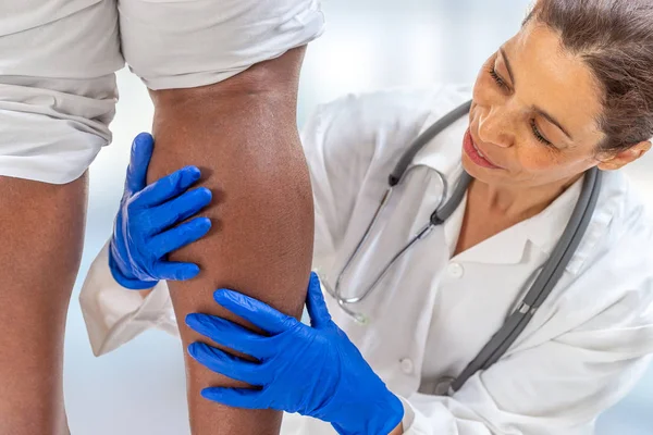 Phlébologue inspectant une jambe de femme à la recherche de varices sur fond blanc — Photo