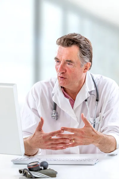 Consulta médica en línea: Doctor expplaining diagnosis while sitting in hfront computer with patient — Foto de Stock