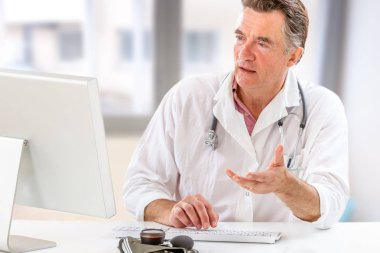 Online medical consultation: Doctor expplaining diagnosis while sitting in hfront computer with patient clipart