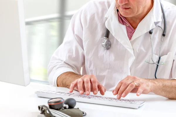 Médico gravando diagnóstico fechar a mão no teclado, enquanto sentado na mesa branca no hospital , — Fotografia de Stock