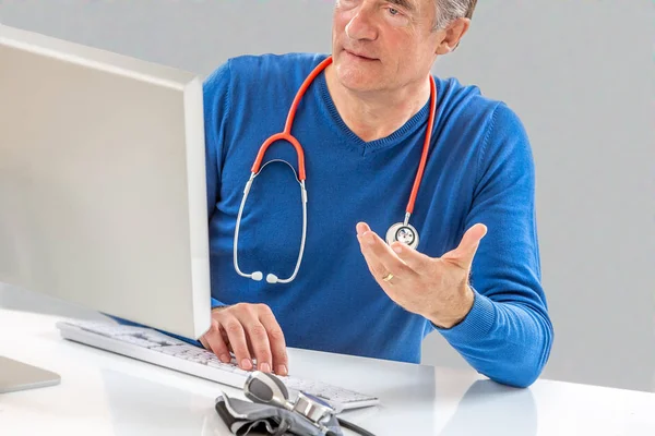 Consulta médica en línea: Doctor expplaining diagnosis while sitting in hfront computer with patient — Foto de Stock
