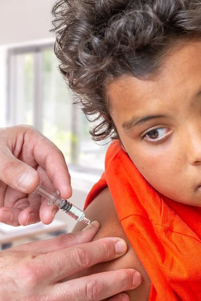 Детская инъекция. 10-12r-летний мальчик, смотрящий как вакцина, препарат вводят ей в руку. врач — стоковое фото