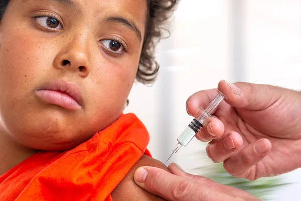 Childhood injection. 10-12r-old boyt watcing as vaccine,a drug is injected into her arm. by doctor — Stock Photo, Image