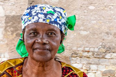 Portrait of African senior citizen woman in her 70- with a happy face in gold and brown dress clipart