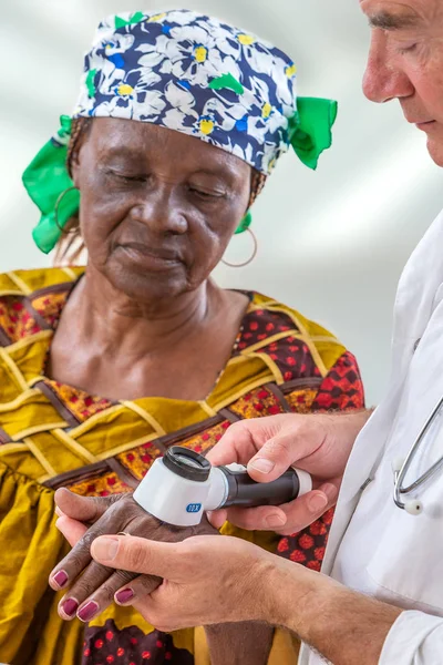 Femme âgée obtenant check-up chez le dermatologue., loupe usig pour voir taupe — Photo