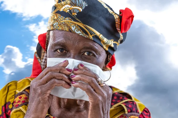 Senior afrcan vrouw met een gewone verkoudheid waait zijn neus met een tissue — Stockfoto