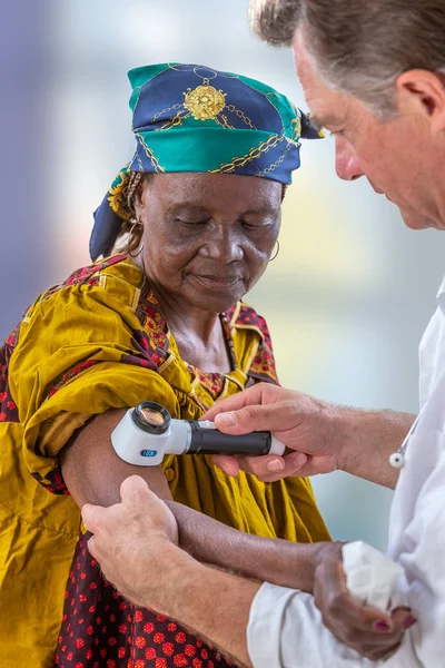 Oudere vrouw krijgen check-up bij dermatoloog., Usig Vergrootglas — Stockfoto