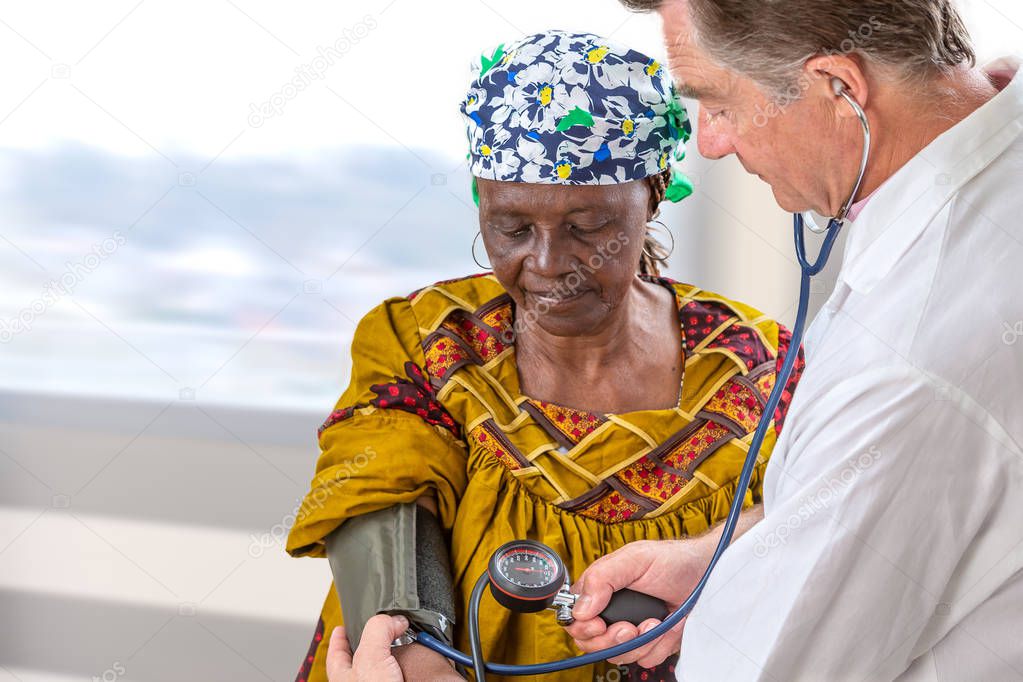 doctor in wite coat measuring blood pressure of anfivan olf woman in hospital