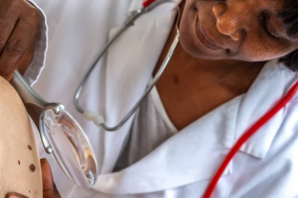 Elderly woman getting check-up at dermatologist.,usig magnifying glass — Stock Photo, Image