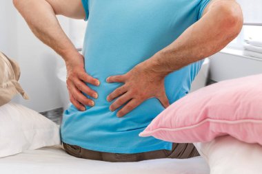 Son sınıf öğrencisi, sırt ağrısı çekiyor. Hasta, dinlendikten sonra yataktan kalkıyor.