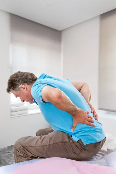 Sénior do sexo masculino sofrendo dor nas costas afiada, pessoa doente se levantar da cama, após o descanso — Fotografia de Stock