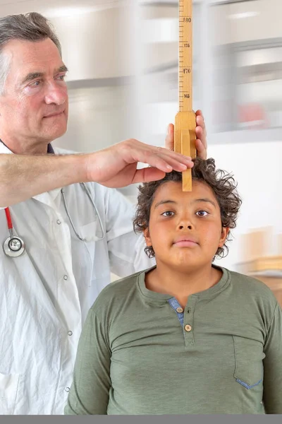 A doctor measures the height of a boy teenager during medical consultation -12-14-years — Stock Photo, Image