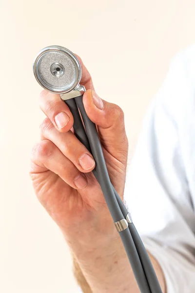 Close-up of a male doctor s hand holding a stethoscope outstretched towards the viewer. Healthy lifestyle concept. Copy space. — Stock Photo, Image