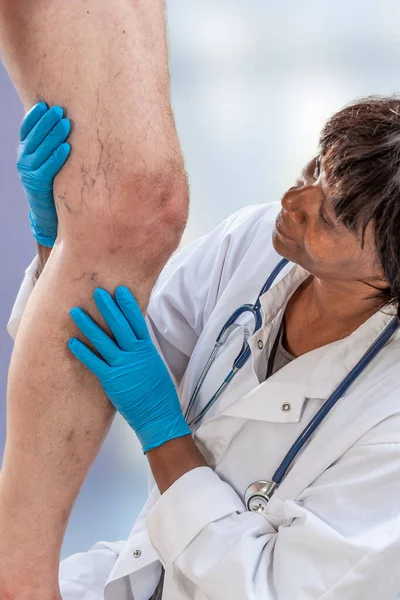 Imagem de close-up do médico fêmea mastigando joelho do paciente masculino — Fotografia de Stock