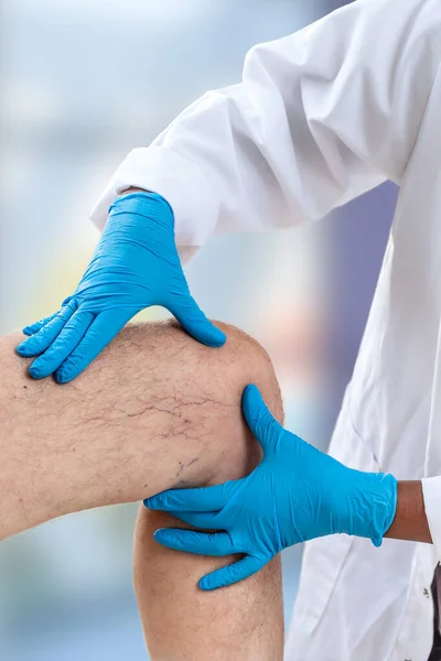 Imagen de primer plano del médico femenino haciendo pipí en la rodilla del paciente masculino — Foto de Stock