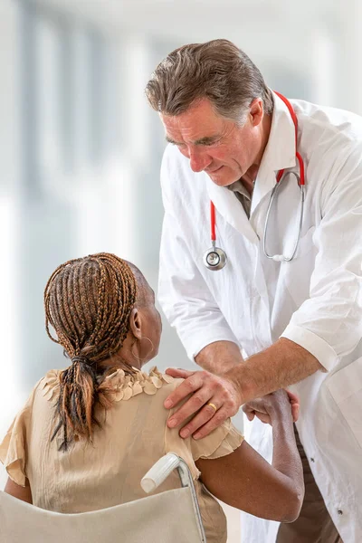 Vriendelijke dokter handdruk gehandicapte vrouw met menselijkheid in het ziekenhuis — Stockfoto