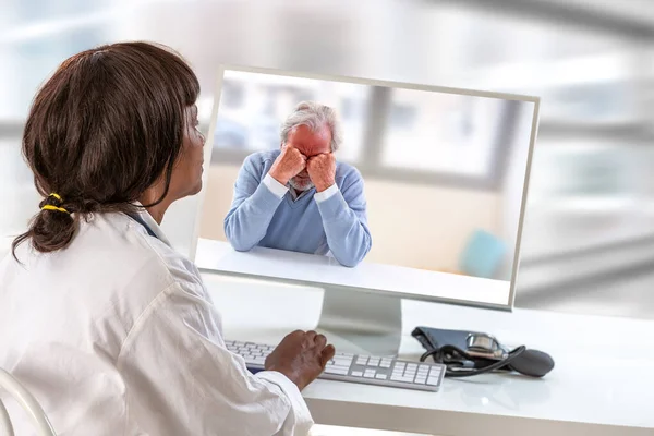 Médico con n frente a su computadora portátil durante una videollamada con un paciente con fibromialgia que tiene problemas para dormir, dolores de cabeza, depresión — Foto de Stock