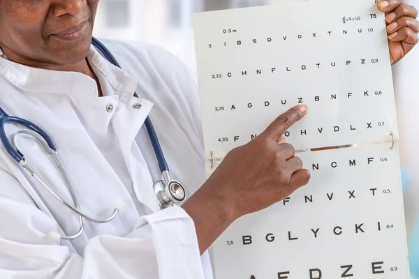 Oftalmologista verificando a visão do paciente, apontando letras, exame de olhos no escritório — Fotografia de Stock