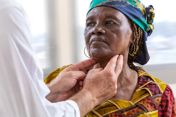 Médico masculino examinando a mujeres ancianas africanas con dolor de garganta en el hospital — Foto de Stock