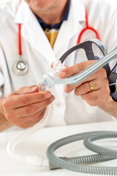 Doctor demonstrating Treatment of sleep apnea and snoring for patient suffering from Obstructive Sleep Apnea Syndrome OSAS connected to a continuous positive airway pressure device CPAP