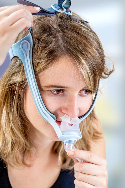 Женщина пытается носить маску CPAP, терапию апноэ во сне
.