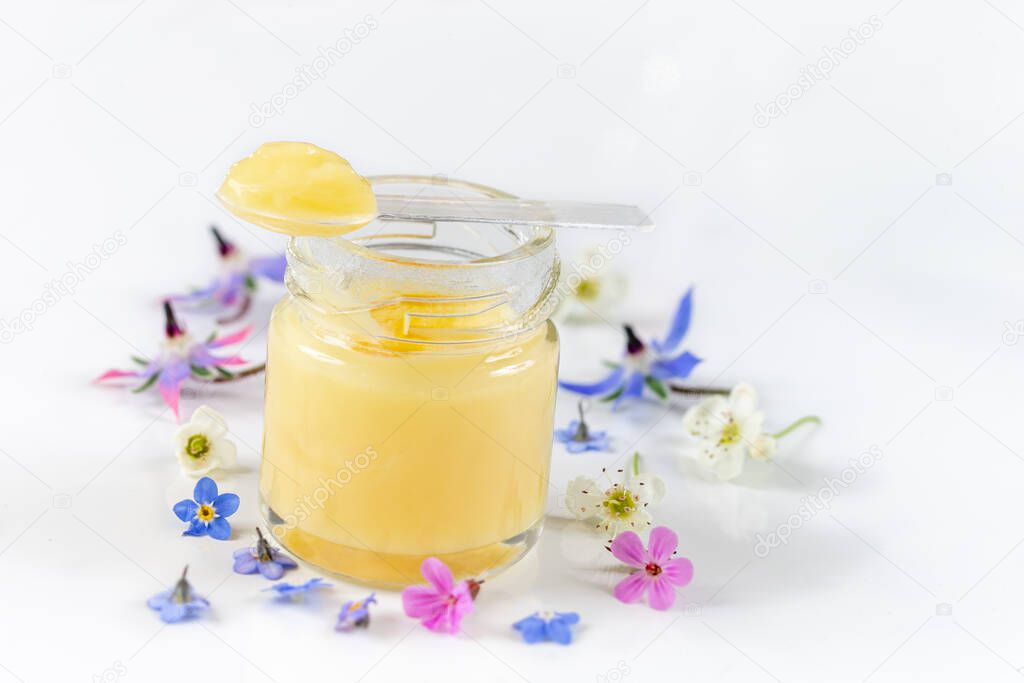 Raw organic royal jelly in a small bottle with litte spoon on small bottle on white background,
