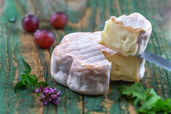 Französischer Saint-Albray-Käse, Scheiben auf Holzschneidebrett, rustikaler Stil mit Trauben — Stockfoto
