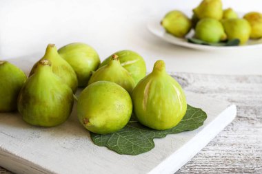 İncir meyvesi. Tahta kesme tahtasındaki bir grup taze yeşil incir, beyaz arka plan. Sağlıklı ve vejetaryen yemekleri. Yakın plan..