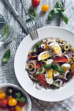 Haşlanmış yumurtalı ev yapımı salata, taze sebze ve ahşap arka planda fesleğen. Hecelenmiş salata. Sağlıklı yiyecekler. Tam üstte.