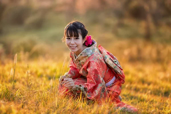 タイのヒマラヤの桜の庭に日本の伝統的な着物と赤い傘を着たアジアの女性 — ストック写真