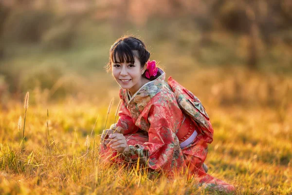 タイのヒマラヤの桜の庭に日本の伝統的な着物と赤い傘を着たアジアの女性 — ストック写真