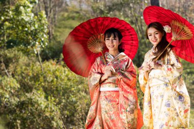 Tayland 'daki Himalaya Sakura bahçesinde geleneksel Japon kimonosu ve kırmızı şemsiye giyen Asyalı kadınlar..