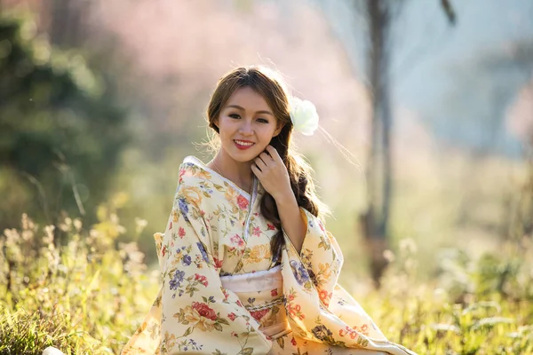 タイのヒマラヤの桜の庭に日本の伝統的な着物と赤い傘を着たアジアの女性 — ストック写真