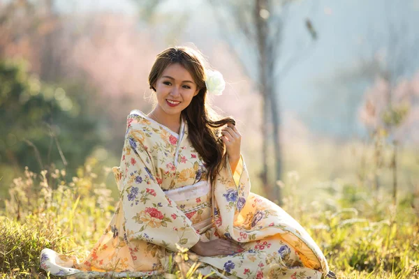 タイのヒマラヤの桜の庭に日本の伝統的な着物と赤い傘を着たアジアの女性 — ストック写真