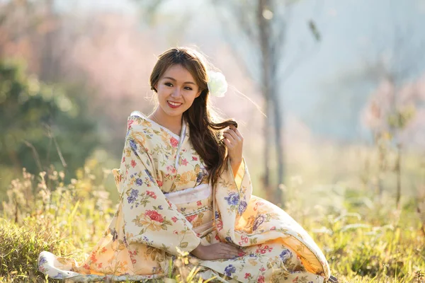 タイのヒマラヤの桜の庭に日本の伝統的な着物と赤い傘を着たアジアの女性 — ストック写真