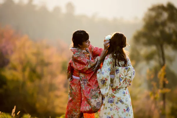 タイのヒマラヤの桜の庭に日本の伝統的な着物と赤い傘を着たアジアの女性 — ストック写真