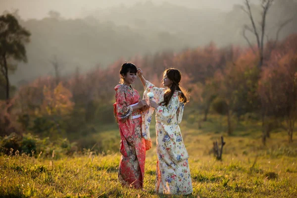 タイのヒマラヤの桜の庭に日本の伝統的な着物と赤い傘を着たアジアの女性 — ストック写真