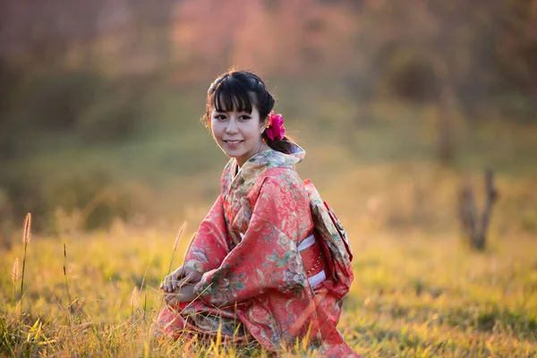タイのヒマラヤの桜の庭に日本の伝統的な着物と赤い傘を着たアジアの女性 — ストック写真