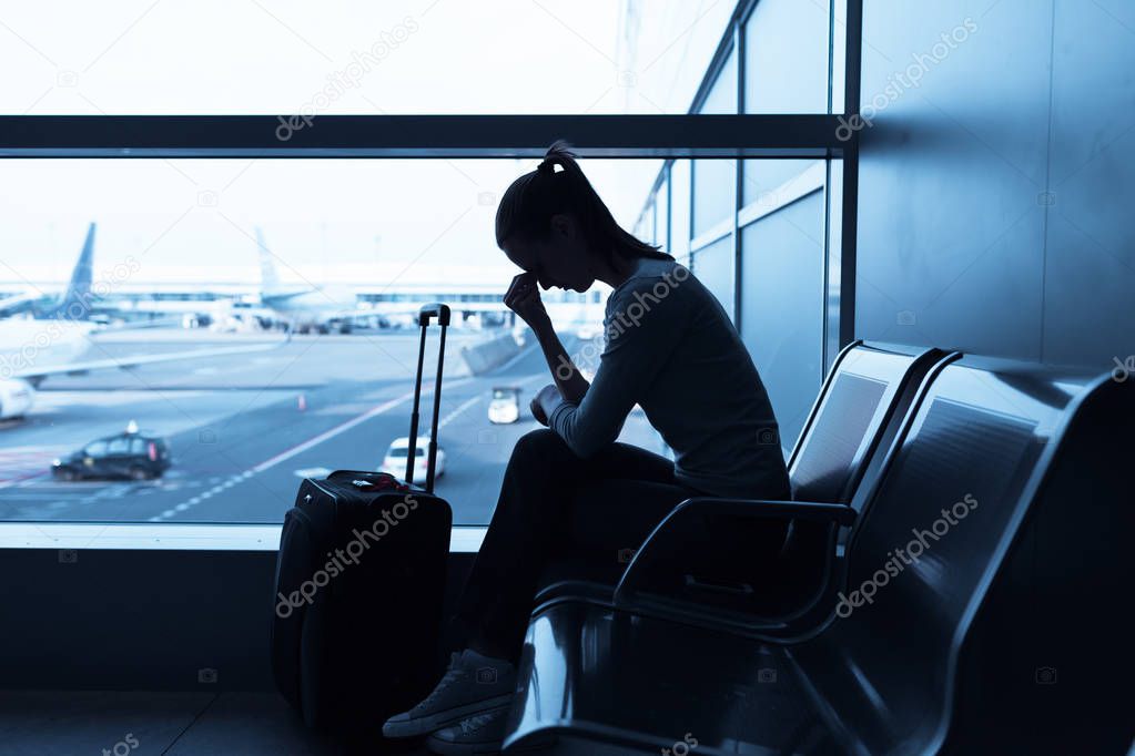 Stressed woman at the airport holding smart phone. 