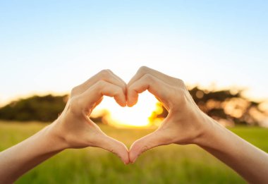 Güzel gün batımına karşı el şeklinde kalp. 