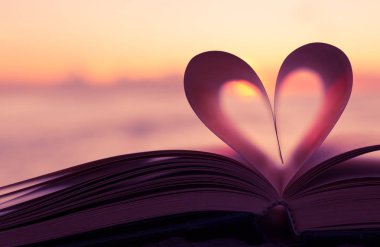 Bir kitap sayfası güzel bir gün batımı karşı yürekten. 