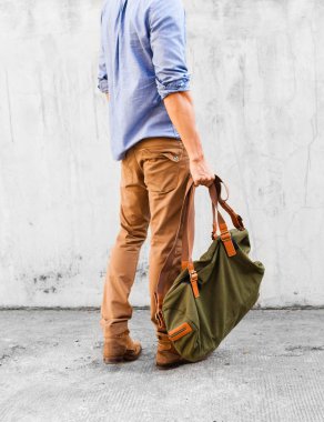 Kot pantolonlu bir adam çanta tutuyor.. 