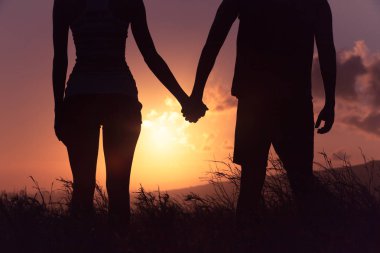 Gün batımında el ele tutuşan çift.